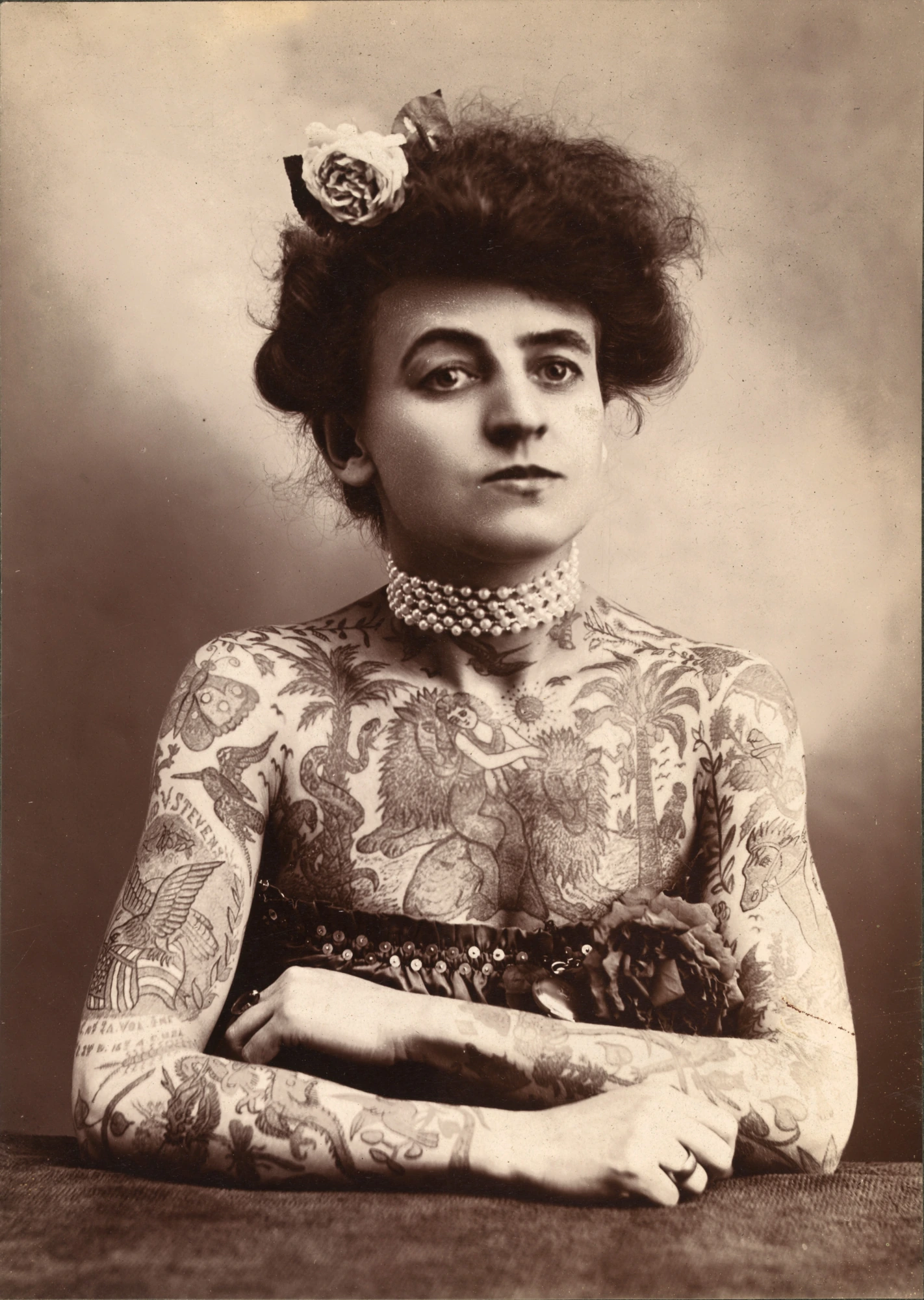 Retrato de Maud Stevens Wagner con los brazos cruzados y tatuajes visibles en brazos y pecho.
